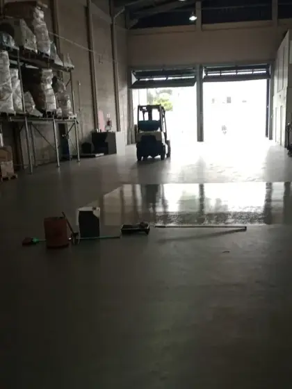 Aplicação de revestimento epóxi em piso industrial, com ferramentas e linha de acabamento visível